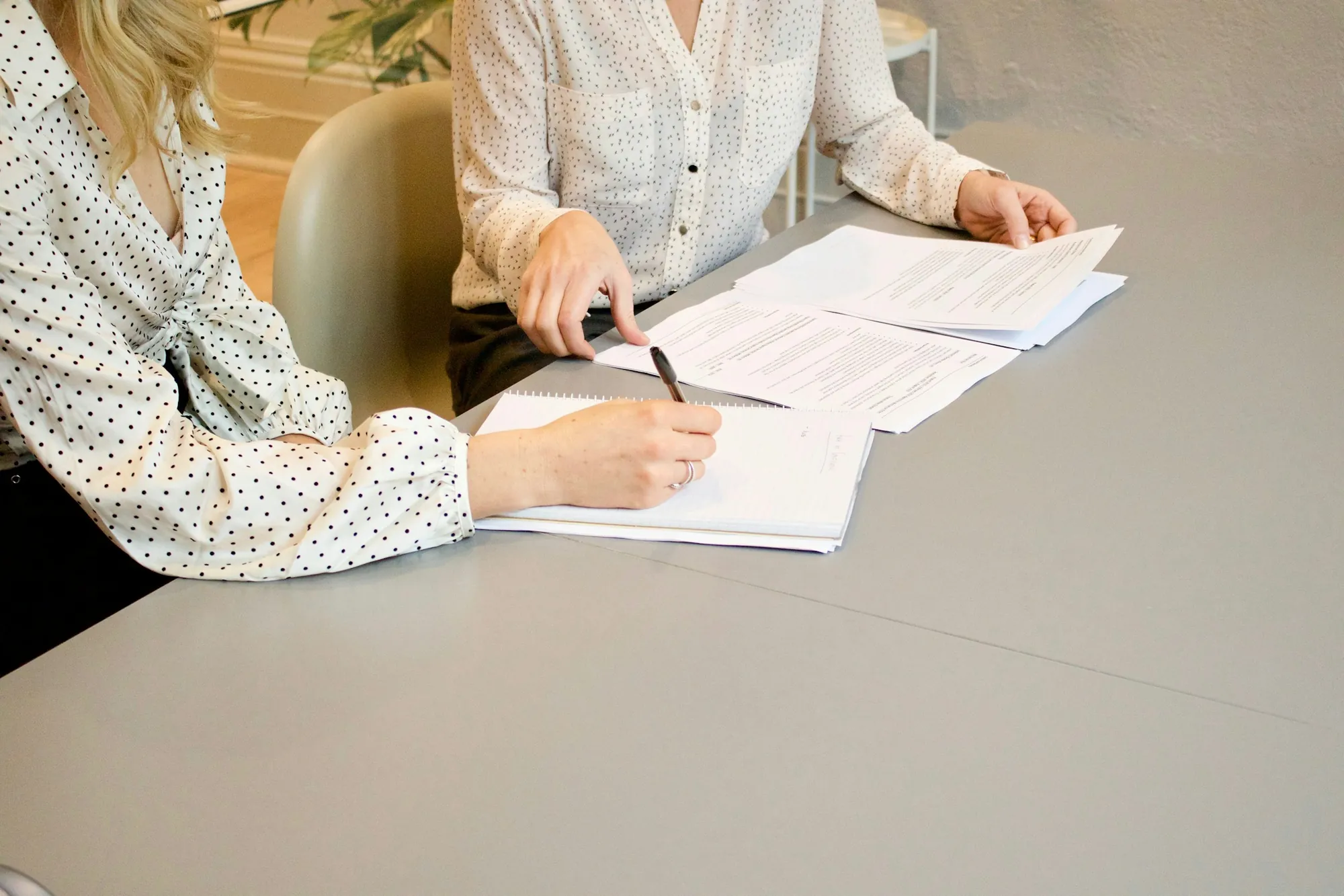 Two people reviewing and signing papers at a table